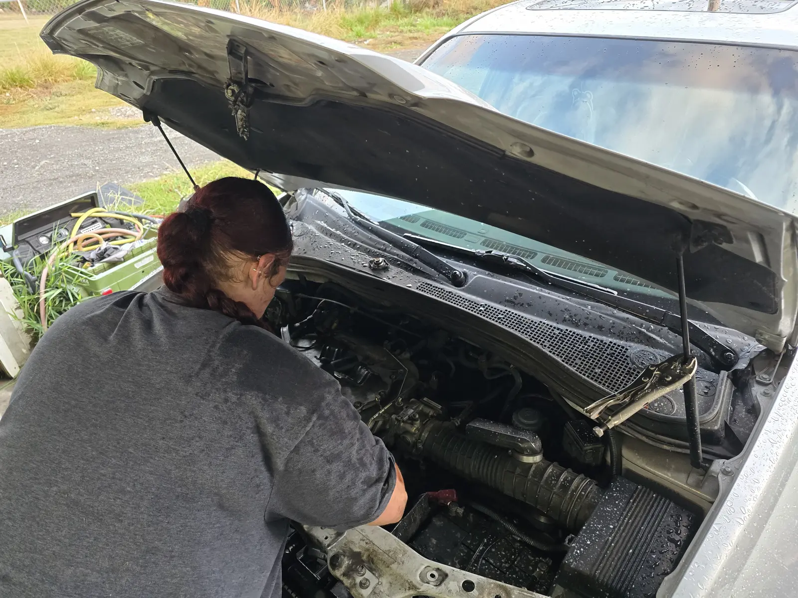 Silver sedan with the hood up, engine bay service